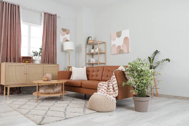 İçinde kahverengi kanepe, masa ve perdeler olan oturma odası.