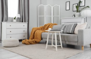 Gri kanepesi, masası ve perdesi olan oturma odasının içinde.