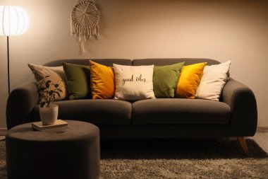 Akşamları kanepe, puf ve parlayan lamba olan karanlık oturma odasının içinde.