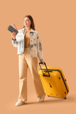 Bej arka planda çantası ve bavulu olan bir kadın yolcu.