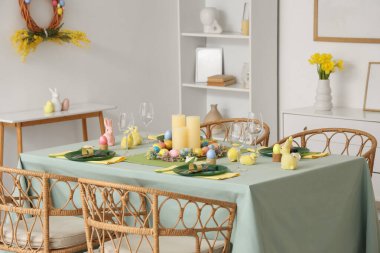 Yemek odasında dekoratif tavşanlar ve paskalya yumurtaları olan güzel bir masa.