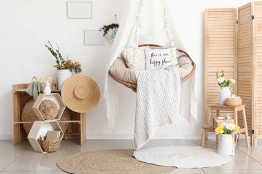 Paskalya için dekore edilmiş oturma odasının içinde asılı sandalye, raflar ve katlanır ekran var.