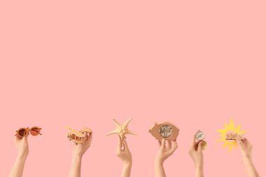 Plaj aksesuarları ve pembe arka planda domuz kumbarası olan kadın eller.