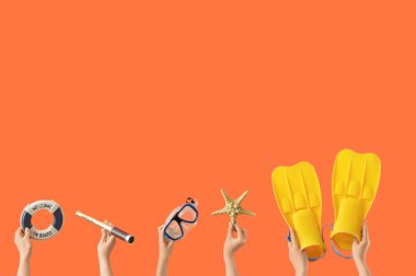Turuncu arka planda plaj aksesuarları olan kadın elleri.