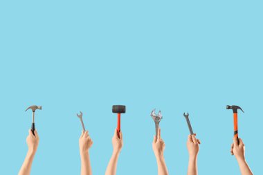 Mavi arka planda İngiliz anahtarı ve çekiçli bir sürü el