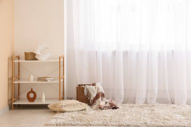 Raflarda halı kaplı sepet var. Odada ışık perdesi var.