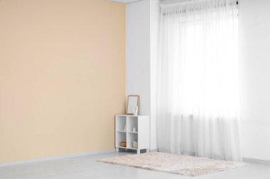 Odada ışık perdesinin yanında çerçeveli ve dekorlu raf ünitesi