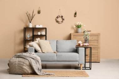 Paskalya için dekore edilmiş oturma odasının içi kanepe, masa ve puf.