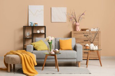 Paskalya için dekore edilmiş oturma odasının içi kanepe, masa ve puf.