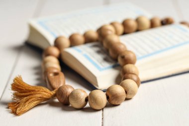 Beyaz ahşap arka planda tasbih içeren Kur 'an. Ramazan kutlaması