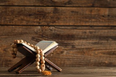 Tahta arka planda tasbih olan bir Kur 'an. Ramazan kutlaması