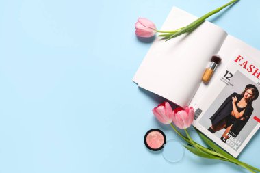 Mavi arka planda çiçekler ve kozmetik ürünleri olan boş moda dergisi. Bahar mevsimi konsepti