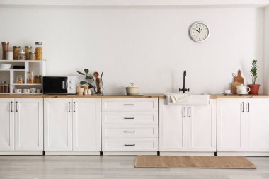 Mutfağın içinde lavabo, mutfak gereçleri ve modern mikrodalga fırın var.