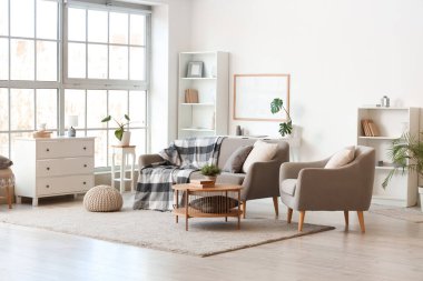 Gri kanepesi, koltuğu ve masası olan bir oturma odası.