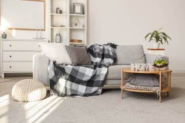 Gri kanepe, masa ve raf ünitesiyle aydınlık oturma odasının içinde.