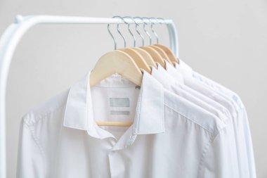 Gri arkaplanda şık beyaz yakalı gömlekler, yakın plan.