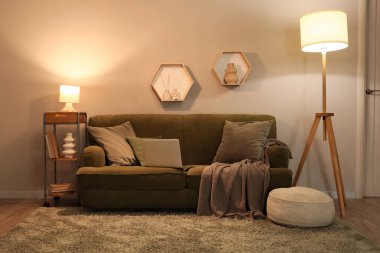 Rahat kanepesi, dizüstü bilgisayarı ve parlayan lambaları olan modern oturma odası.