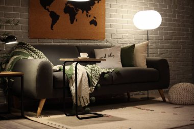 Rahat kanepesi, sehpası ve parlak lambaları olan modern bir oturma odası.