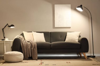 Modern oturma odasının içinde rahat bir kanepe ve parıldayan lambalar.