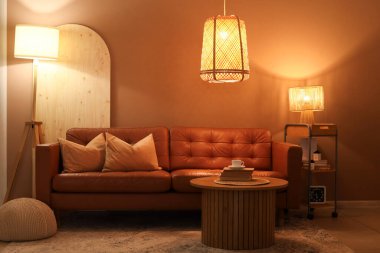 Rahat kanepesi, sehpası ve parlak lambaları olan şık bir oturma odası.