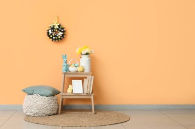 Pouf 'ta yastık ve Paskalya kutlaması için dekore edilmiş bej duvarın yanındaki odada duruyor.