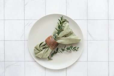 Beyaz fayans zemininde okaliptüs dalları olan güzel masa ayarları