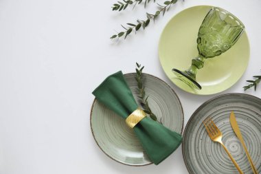 Altın çatal bıçak seti ve gri arka planda okaliptüs dalları olan güzel bir masa.