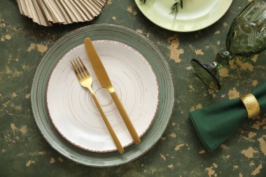 Yeşil arka planda altın çatal bıçak takımı olan güzel bir masa.