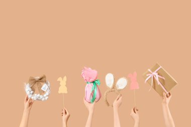 Paskalya dekoru ve bej arka planda hediyeli kadın elleri.