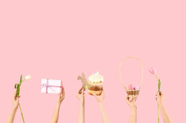 Paskalya pastalı kadın elleri, yumurtalar, laleler ve pembe arka planda hediye