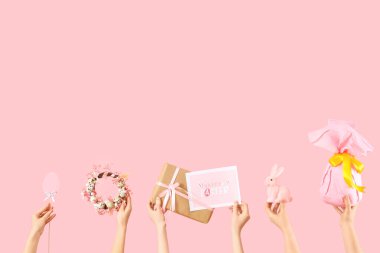 Paskalya dekorlu kadın elleri ve pembe arka planda hediye.