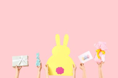 Paskalya dekorlu kadın elleri ve pembe arka planda hediye.