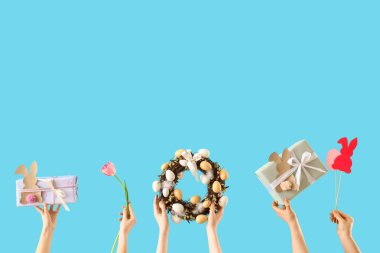 Paskalya dekoru ve mavi arka planda hediye kutuları olan kadın elleri
