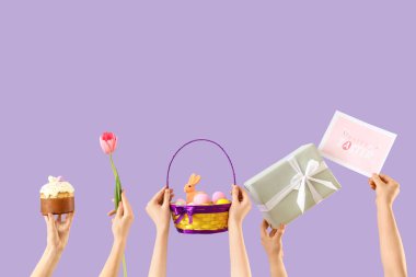 Paskalya pastası, yumurta, lale ve leylak arkaplanda hediyeli kadın elleri.