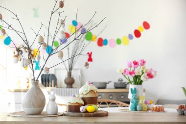 Ağaç dalları olan vazolar, paskalya pastaları ve mutfak masasında yumurtalar.