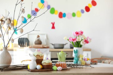 Ağaç dalları olan vazolar, paskalya pastaları ve mutfak masasında yumurtalar.