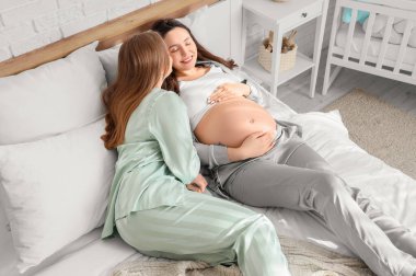 Genç hamile lezbiyen çift yatak odasında yatıyor.