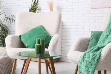 Oturma odasındaki masada yanan yeşil mumlar.