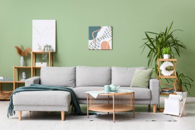 Oturma odasında kanepe, masa ve yeşil bitkiler var.