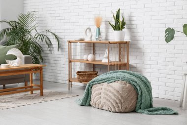 İçinde pouf, raf ünitesi ve yeşil bitkiler olan oturma odası.