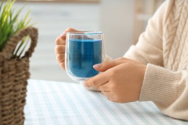 Evde bir fincan lezzetli mavi çayı olan bir kadın. Yakın çekim.