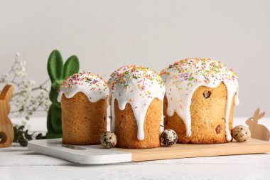 Tatlı Paskalya pastaları, bıldırcın yumurtaları ve beyaz ahşap masada oyuncak tavşancık.