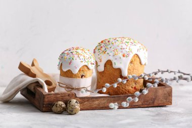 Wooden tray with sweet Easter cakes, quail eggs and pussy willow branches on grey table