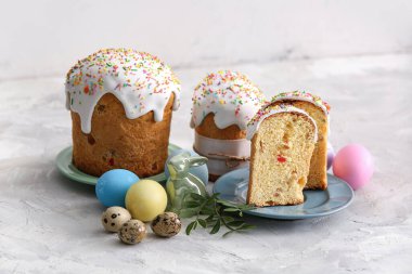 Gri masadaki boyalı yumurtalı ve oyuncak tavşanlı Paskalya pastaları