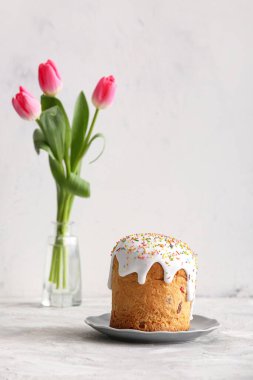 Tatlı Paskalya pastası ve gri masada güzel lale çiçekleri.