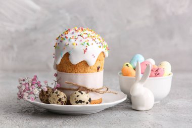 Tatlı Paskalya pastası, bıldırcın yumurtası ve gri arka planda çingene çiçekli tabak.