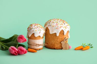 Minik havuçlu Paskalya pastaları ve turkuaz arka planda lale çiçekleri.