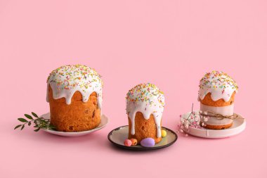 Tatlı Paskalya pastaları, boyalı yumurtalar ve pembe arka planda çingene çiçekleri.