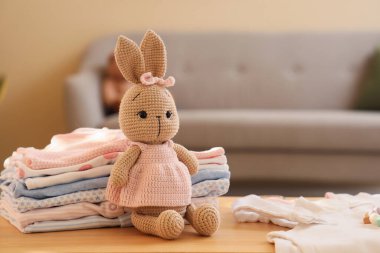 Odada bebek kıyafetleri yığılı oyuncak tavşan, yakın plan.