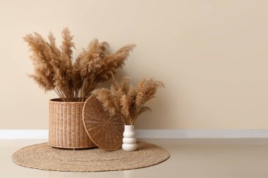 Hasır sepet ve otlar beyaz duvarın yanında.